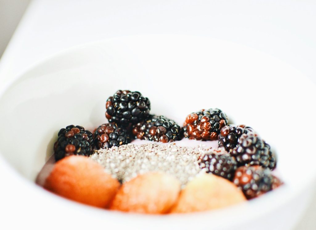 Schüssel mit Beeren, Chiasamen und kleinen Früchten auf hellem Hintergrund.